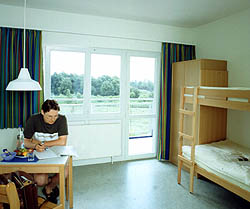 Helles Zimmer mit Stockbett und Blick auf Bäume durch Fenster und Balkontür